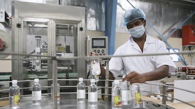 A worker collects completed bottles of white vinegar from an assembly line at the Chilly Willy manufacturing facility in Dubai, June 3, 2015.