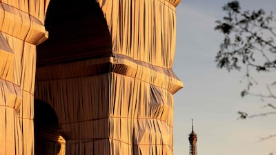 Arc de Triomphe is shown wrapped in fabric, against the Eiffel Tower in the background. The building remained covered for 16 days. AFP