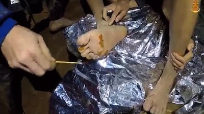 A video grab handout made available by Thai Royal Navy shows a Thai military medic providing first aid to a member of the trapped football team in a section of Tham Luang cave in Khun Nam Nang Non Forest Park. Thai Royal Navy / EPA