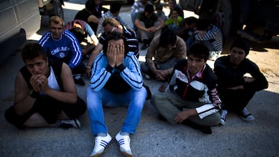 Afghan migrants sit on the ground after being detained by the Greek port police in Lesbos. Uriel Sinai / Getty