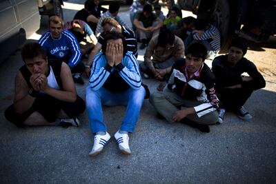 Afghan migrants sit on the ground after being detained by the Greek port police in Lesbos. Getty