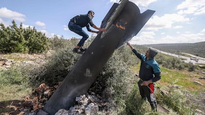 A Palestinian man climbs on an Iranian missile remnant that landed in the occupied West Bank village of Hares. AFP