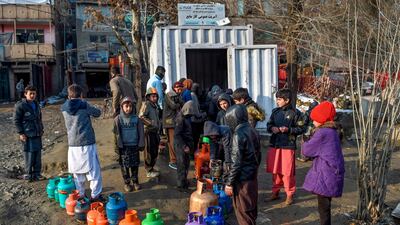 Men and children stand in a queue as they wait to fill canisters with liquid gas at a government gas distribution centre in Kabul. AFP