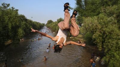 A Pakistani jumps as people cool themselves off in a canal in Lahore, Pakistan, where temperature reached 44 degrees Celsius. AP Photo
