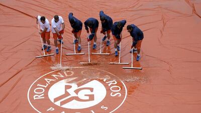 Court workers sweep away rain water at the Suzanne Lenglen court. REUTERS/Gonzalo Fuentes