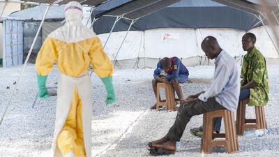 A hygienist in Guinea approaches patients who are awaiting the results of blood tests that will disclose their Ebola status. Sylvain Cherkaoui / Cosmos