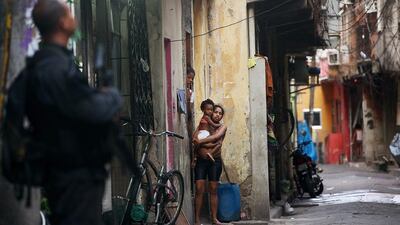Residents look on as Brazilian military police officers patrol the Complexo da Mare. (Mario Tama / Getty Images / March 30, 2014)