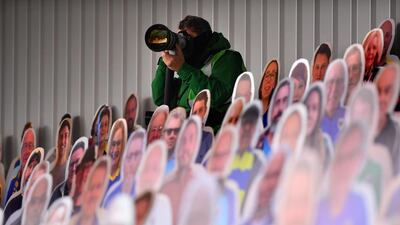 A photographer sits between cardboard cu- out fans during the Sky Bet League One match between AFC Wimbledon and Sunderland at Plough Lane in Wimbledon, England. Getty Images