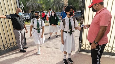 A staff member performs temperature checks as pupils arrive.