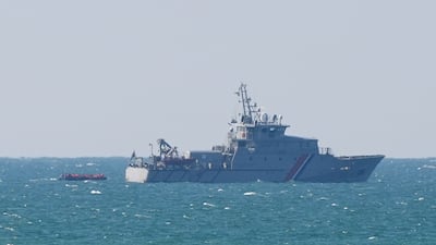 A small boat carrying migrants is escorted by the French authorities as it leaves the coastline near Boulogne in France. PA