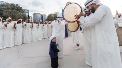 Musicians and dancers demonstrate Emirati dance for a young visitor