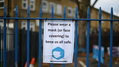 Signage reminding people to wear a mask or face covering is seen on the closed gate of a primary school in east London. AFP