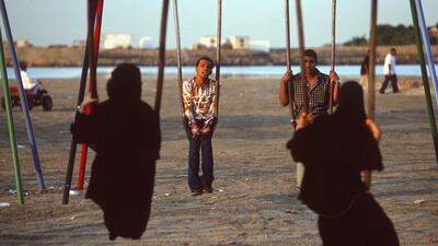 Young men and women on swings on a Jeddah beach in 2002. Alijohani's novel is about difficult relationships in Saudi Arabia. Reza / Getty Images