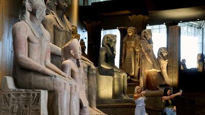 Tourists stand next to museum exhibits displayed at the Grand Egyptian Museum, which will officially open in November 2025. Reuters