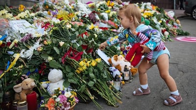 A young girl places a bouquet of flowers in commemoration of the victims of Malaysia Airlines MH17 plane accident in eastern Ukraine in front of the Dutch embassy in Kiev. EPA/ROMAN PILIPEY