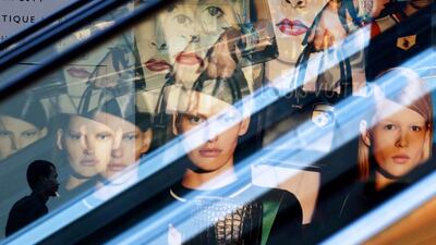 A cleaner walks past a reflection of luxury fashion advertisements at a mall in Singapore. Edgar Su / Reuters