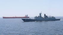 A Pakistan warship escorts a Pakistani merchant vessel. Plans are under way by neutral countries to extract 1,000 ships out of the Arabian Gulf. Reuters