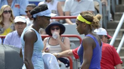 Venus Williams, left, and her sister Serena walk to their seats between games during semifinal play at the Rogers Cup tennis tournament, Saturday, on Aug. 9, 2014 in Montreal. AP Photo/The Canadian Press