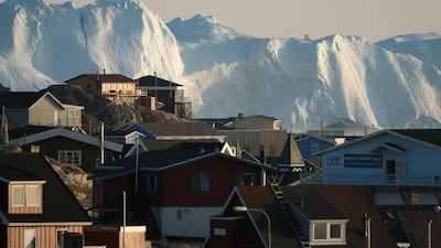Icebergs in the Ilulissat Icefjord loom behind buildings. Getty Images