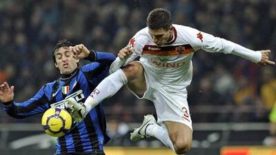 Roma's Marco Andreolli, goes airborne to take the ball away from Inter's Diego Milito on Sunday.