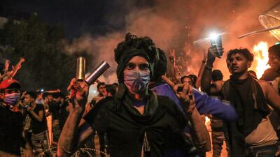A protester with tear gas canisters on his fingers flashes the victory sign during anti-government protests in Karbala, Iraq. AFP
