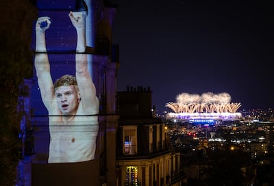 An image of French swimmer Leon Marchand is projected on to a Paris building as the fireworks of the Olympic closing ceremony are seen blasting out of the Stade de France. Getty Images