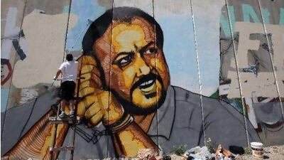 A Palestinian artist finishes a portrait of jailed Palestinian Fatah leader Marwan Barghuti on a cement barrier near the Israeli-controlled Qalandia checkpoint, between Jerusalem and Ramallah. AFP