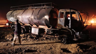 A Pakistani policeman stands beside wreckage of a burnt out oil taker and passenger bus following an accident in Sindh Province, on January 11, 2015. AFP PHOTO/ Asif Hassan