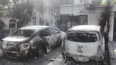Pakistani security personnel stand next to burned out vehicles in front of the Chinese consulate after an attack in Karach. AFP