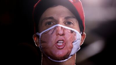 A supporter wearing a Trump face mask looks on as US President Donald Trump holds a campaign rally at Middle Georgia Regional Airport in Macon, Georgia, USA. Reuters