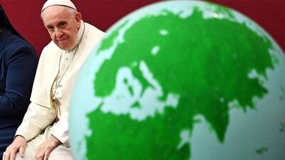 Pope Francis looks at a globe of the Earth during an audience for children and families of the Santa Marta dispensary. AFP