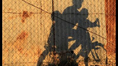 Palestinian children cast shadows against a metal gate as they ride a bicycle on a street along the beach of Gaza City. Mohammed Salem / Reuters