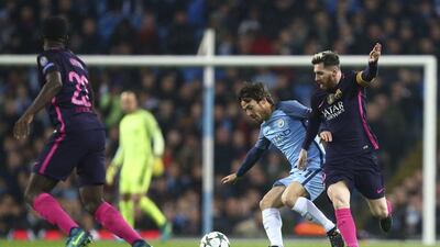 Manchester City midfielder David Silva shields the ball from Lionel Messi. Dave Thompson / AP Photo