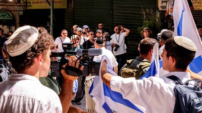 An Israeli right-wing activist obscures the camera of a video journalist with an Israeli national flag. AFP