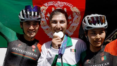 Afghanistan's Fariba Hashimi celebrates with teammates Yuldoz Hashimi and Zahra Rezayee after clinching a silver medal in the women's road race at the Asian Games - Aichi-Nagoya 2026. Reuters
