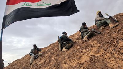 Fighters from the Shiite Hashed Al Shaabi paramilitary unit sit under an Iraqi flag as they get ready to advance towards the village of Shwah, south of the city of Tal Afar on the western outskirts of Mosul. Ahmad Al Rubaye / AFP Photo