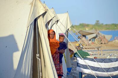 A displaced flood-affected woman stands with her child at a makeshift camp alongside flood waters in Jaffarabad district of Balochistan province on October 5, 2022. AFP