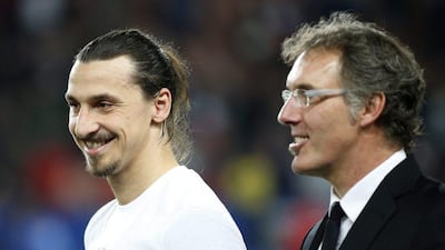 Zlatan Ibrahimovic of Paris Saint-Germain and Paris Saint-Germain head coach Laurent Blanc wait on the pitch after winning the Ligue 1 title. Yoan Valat / EPA / May 7, 2014