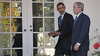 George W Bush and Barack Obama walk through the White House grounds.