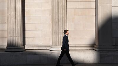 A city worker walks past the Bank of England in the City of London. Senior M&A advisers can earn up to £350,000 per year, a new study found. EPA