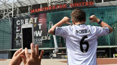 A boy poses for pictures after purchasing a Manchester United shirt with the name and squad number of recent signing French midfielder Paul Pogba outside Old Traford in Manchester on August 9, 2016. AFP / PAUL ELLIS