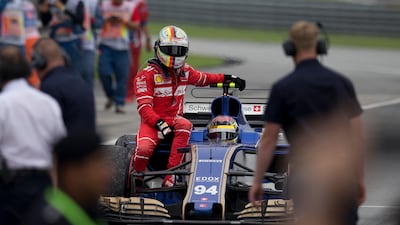 Ferrari driver Sebastian Vettel returns to the pit area with a ride from Sauber driver Pascal Wehrlein after the Malaysian Grand Prix in Sepang. Thomas Lam / AP Photo