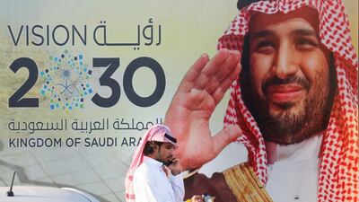 A Saudi man carries his coffee pot as he walks past a banner showing Saudi Crown Prince Mohammed bin Salman, outside a mall in Jeddah, Saudi Arabia. AP Photo
