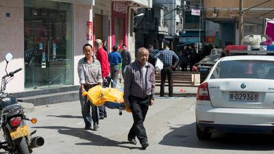 People carry out the covered body of the attacker who allegedly stabbed 10 children at a school in Haikou, Hainan province on February 29, 2016. Reuters