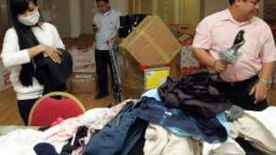 Volunteers Sheila Cabawatan, from left, and Ronald Queddeng help Robert Ramos, a community leader, organise donations at Reef Mall.