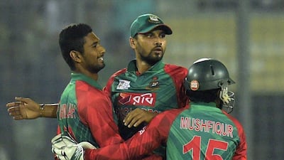 Bangladesh cricket captain Mashrafe Mortaza (C) congratulates teammate Mohammad Mahmudullah (L) alongside wicketkeeper Mushfiqur Rahim (R) after the dismissal of unseen Indian batsman Suresh Raina during a Twenty20 cricket match between India and Bangladesh for the Asia Cup T20 cricket tournament at The Sher-e-Bangla National Cricket Stadium in Dhaka on February 24, 2016. AFP PHOTO/Munir uz ZAMAN