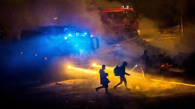 Migrants evacuating a huge fire at the Grande-Synthe migrant camp outside the northern French city of Dunkirk on April 10, 2017, which was reduced to 'a heap of ashes', according to the regional chief. Philippe Huguen/AFP