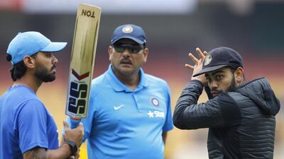 Virat Kohli, right. holds his hands as if wielding a baseball bat. Aijaz Rahi / AP Photo
