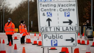People stand behind a sign showing the way to the NHS Vaccination Centre in Manchester. Reuters