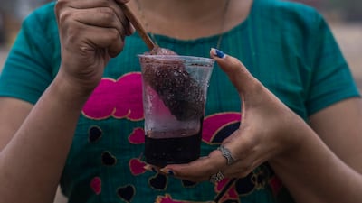 A girl prepares to drink shaved ice at Juhu beach in Mumbai. AP